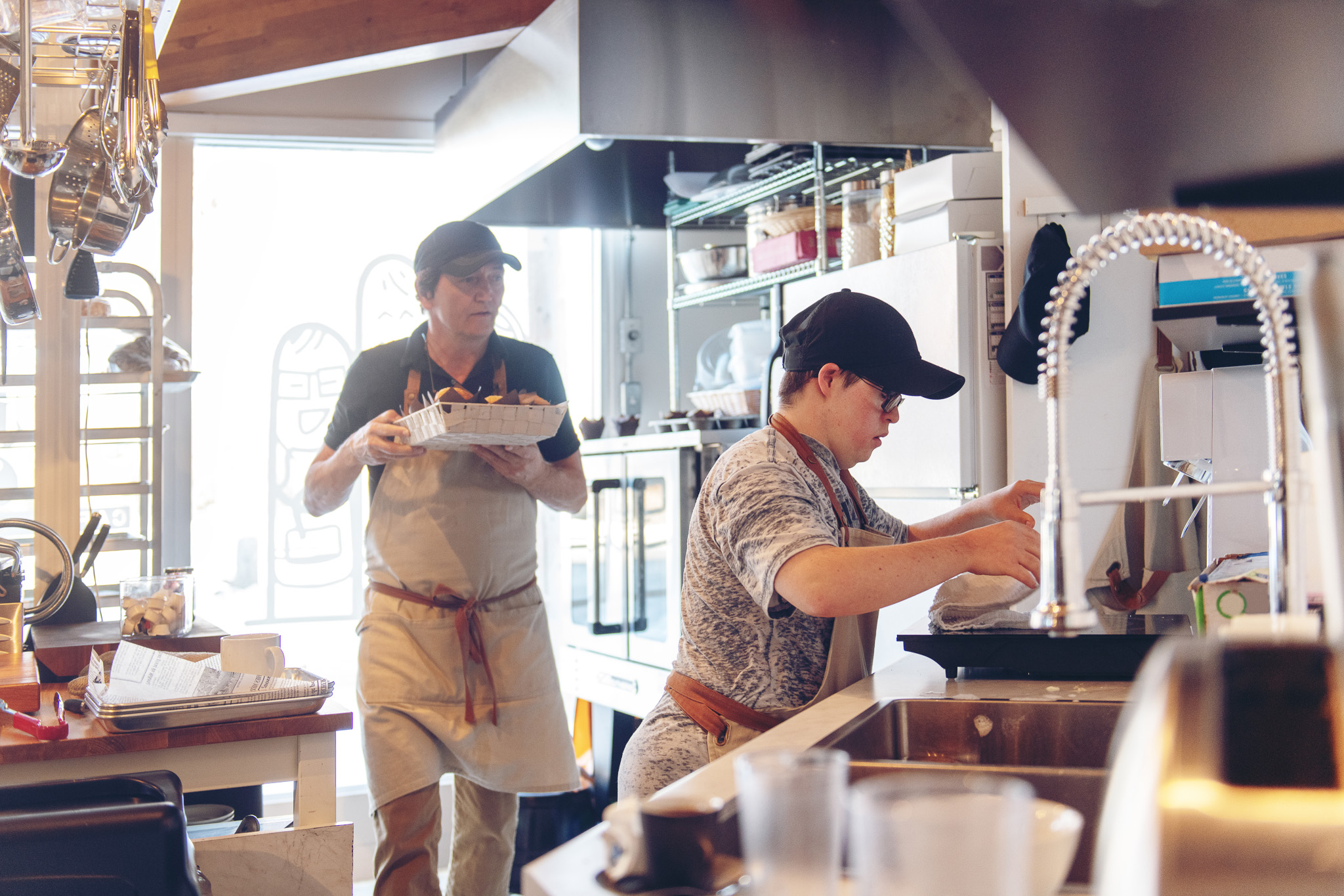 zwei Personen arbeiten in einem Cafe an der Kaffeemaschine