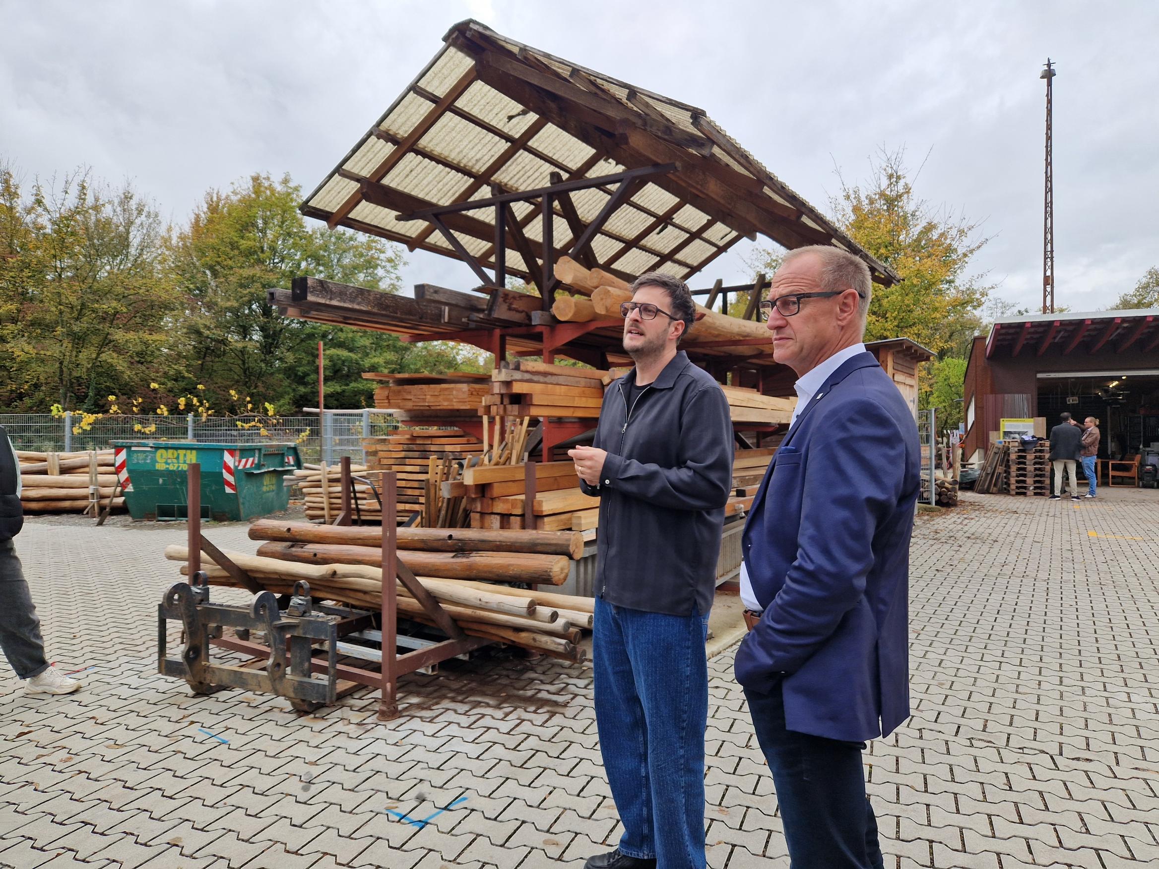 zwei Personen auf einem Gelände mit viel Holz