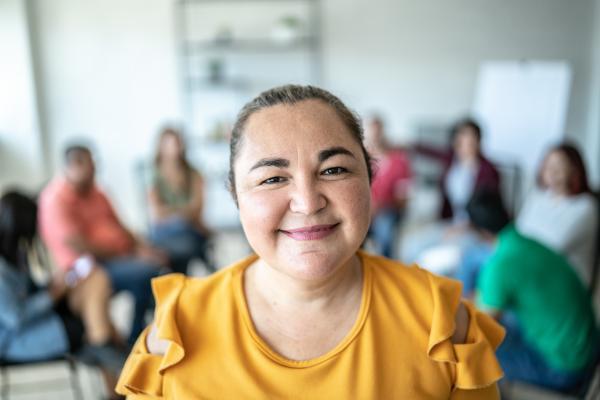 Junge Frau in gelbem Shirt blickt fröhlich 