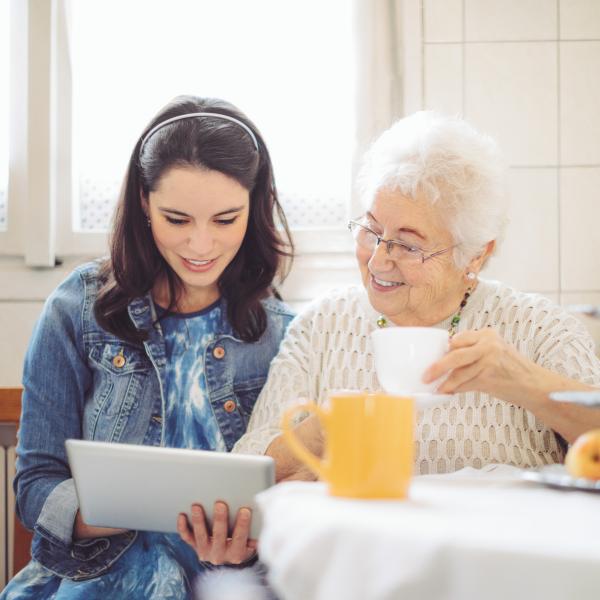 junge Frau sitzt mit Seniorin am Küchentisch
