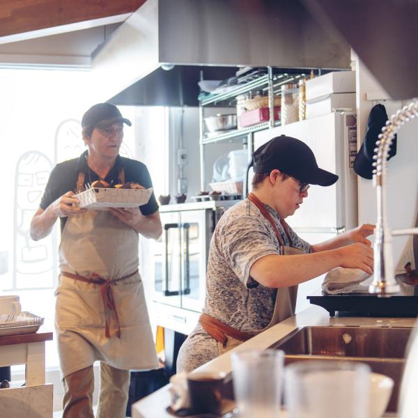 zwei Personen arbeiten in einem Cafe an der Kaffeemaschine