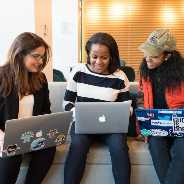 3 junge Frauen mit Laptops tauschen sich aus