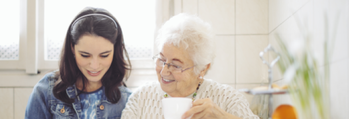 junge Frau sitzt mit Seniorin am Küchentisch