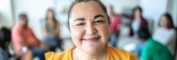 Junge Frau in gelbem Shirt blickt fröhlich 