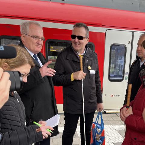 Rainer Wieland im Austausch mit sehbehinderten Menschen am S-Bahnsteig