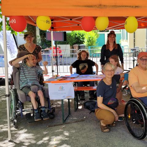 8 Personen stehen und sitzen um den Infostand
