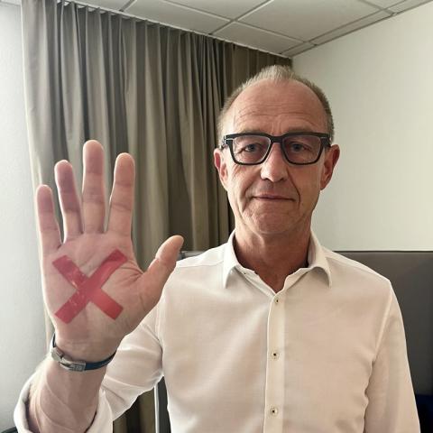 Portrait Vorstand Ulf Hartmann mit rotem X in der Handinnenfläche