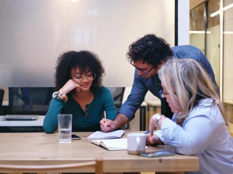 ein Mann erklärt zwei Frauen etwas in einem Dokument