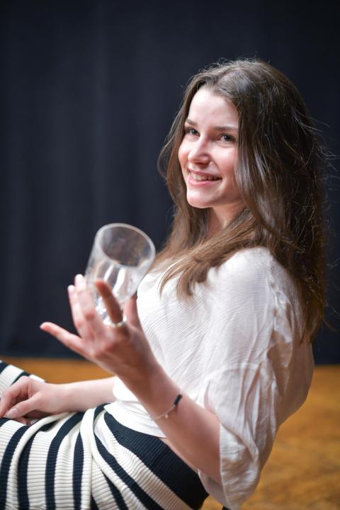 junge Frau sitzt auf einem Stuhl mit einem Glas Wasser in der Hand