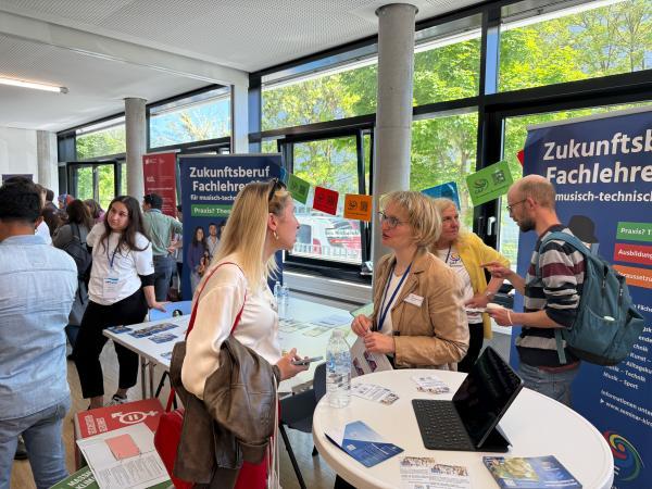 Informationsstand mit 4 Menschen vor Rollups und an Tischen