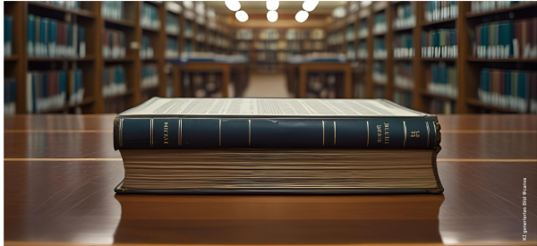 Ein dickes Buch liegt auf dem Tisch in einer Bibliothek