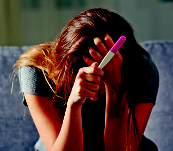 Frau mit Schwangerschaftstest stützt den Kopf in die Hände