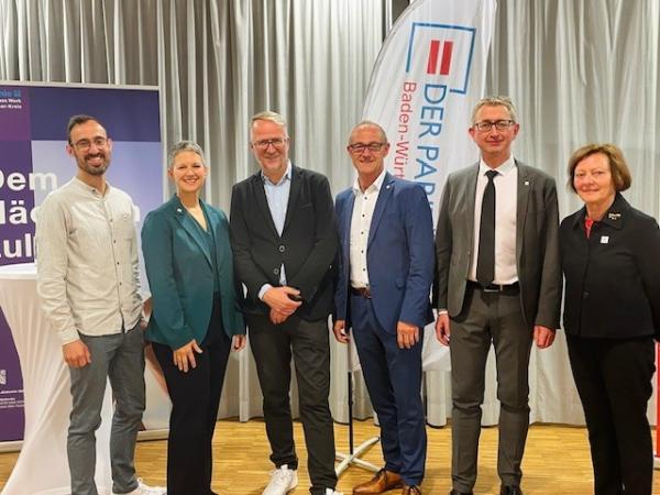 Mehrere Menschen stehen vor einer Bühne mit Paritätischem Banner