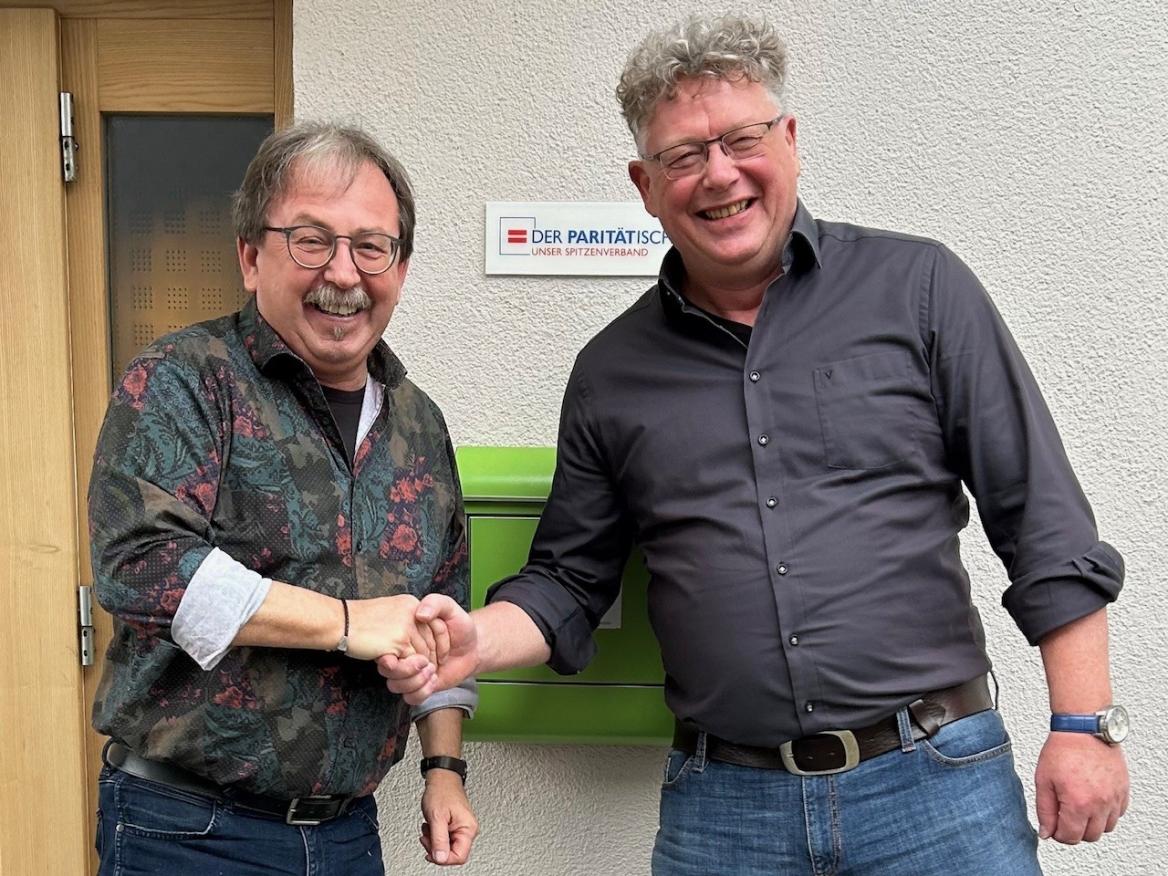 zwei Männer schütteln sich lachend die Hand