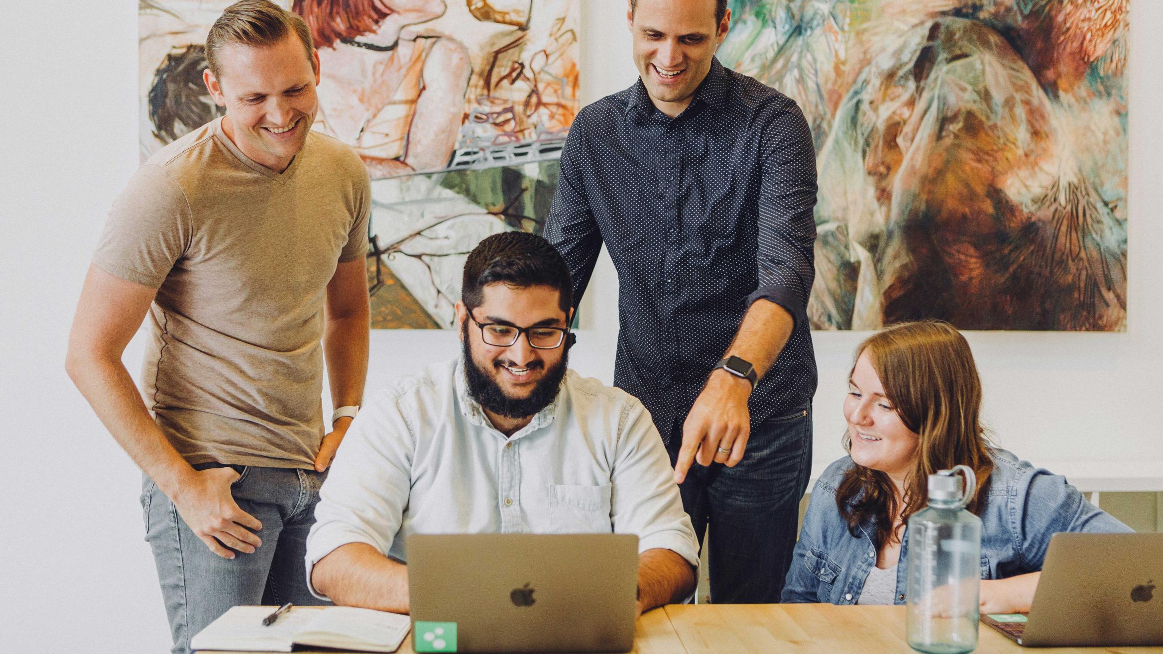 Drei Personen beraten einen Menschen am Computer