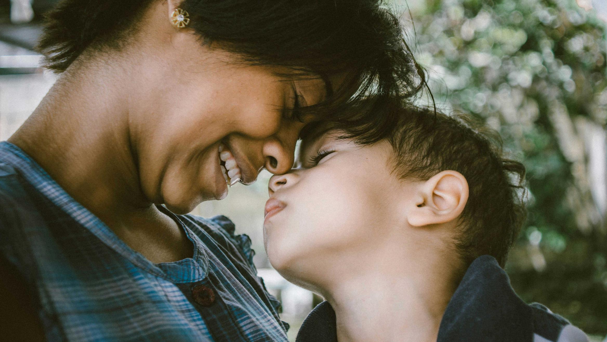 Eine Frau und ein Kind lehnen vertraut die Köpfe aneinander