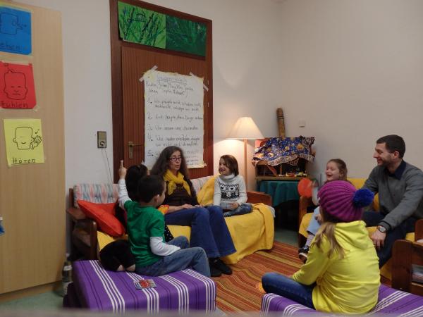 Kinder sitzen im Kreis mit Erwachsenen und unterhalten sich