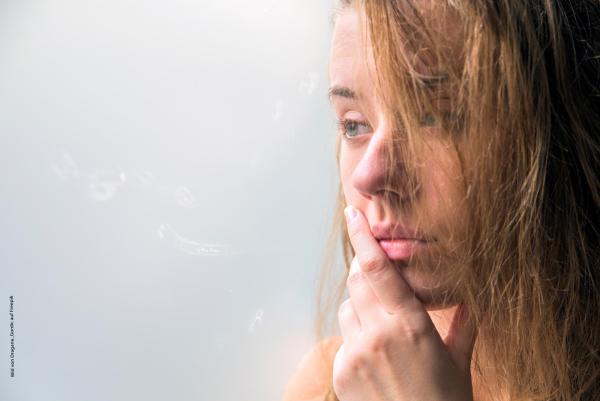 Frau mit dunkelblonden Haaren mit Hand am Mund