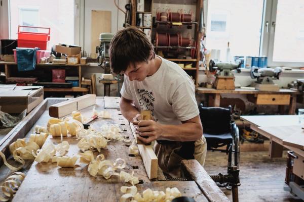 Junger Mann bei Holzarbeiten in Tischlerei