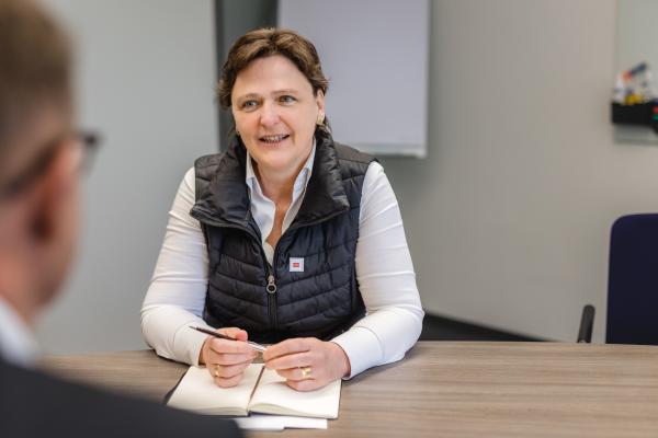 Frau mit braunen Haaren sitzt am Schreibtisch