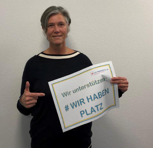 Frau mit Plakat in der Hand "Wir haben Platz"
