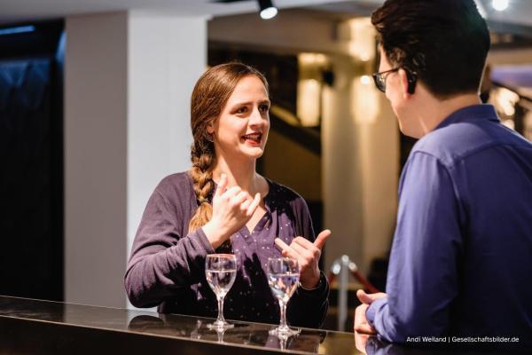 Frau spricht mit Mann am Tresen stehend in Gebardensprache