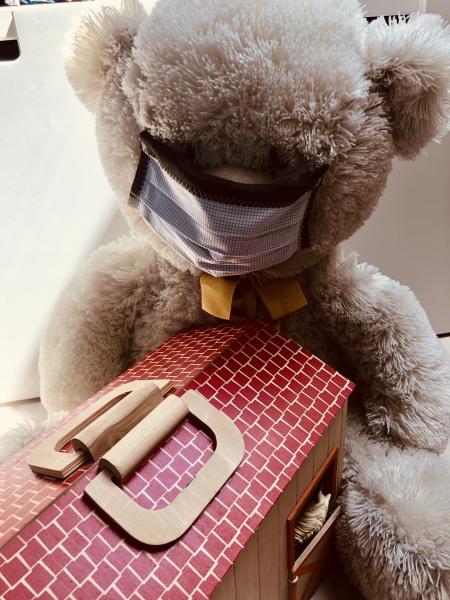 Weißer Teddybär mit gestreiftem Mund-nasen-Schutz