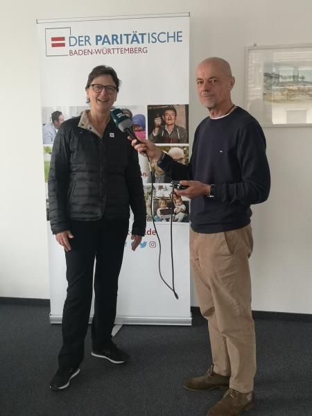 Mann interviewt Frau vor Banner stehend