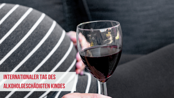 Schwangere Frau hält ihren sBauch und ein Glas Rotwein in der Hand