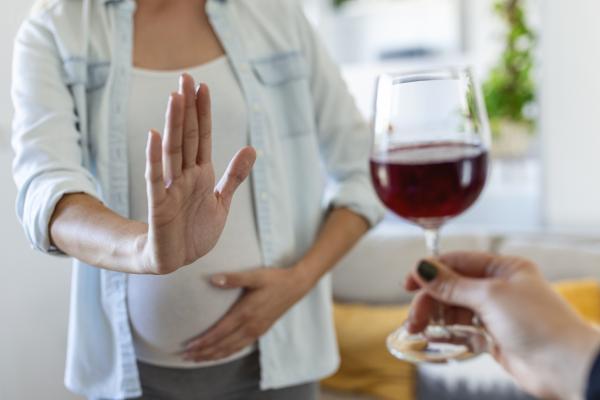 Schwangere Frau lehnt Glas Wein ab