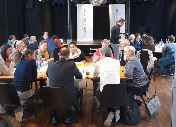 Drei Thementische mit diskutierenden Menschen