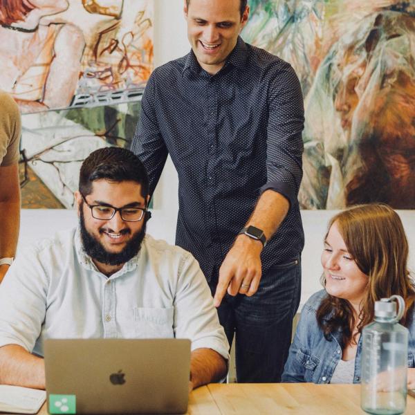 Drei Personen beraten einen Menschen am Computer