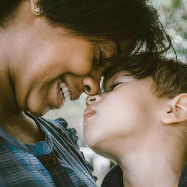 Eine Frau und ein Kind lehnen vertraut die Köpfe aneinander
